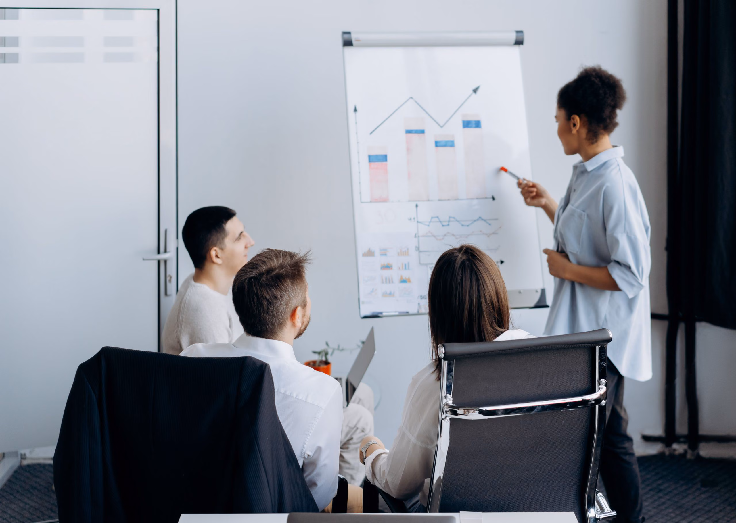 Presenter at a flip chart showing a trend line to seated colleagues