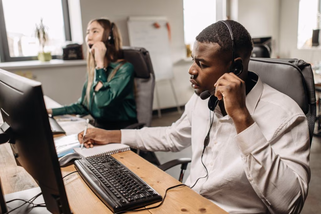Two contact centre agents in headsets taking calls at desktop workstations