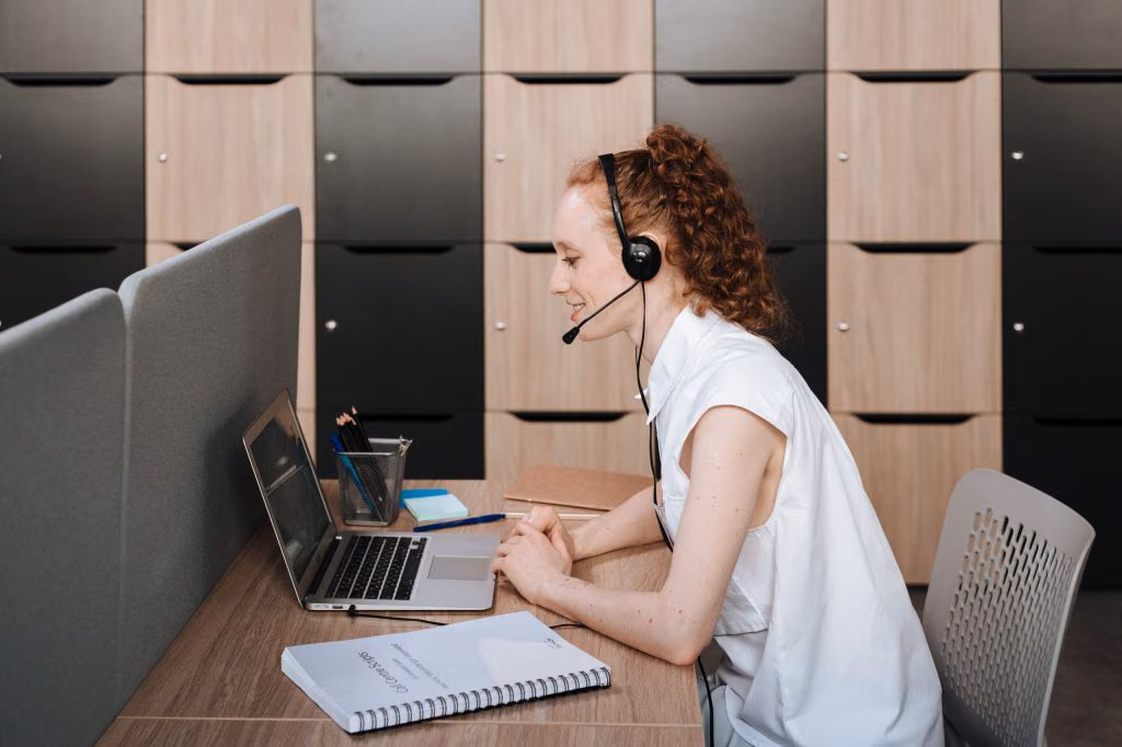 Contact centre agent in a headset working at a laptop in a cubicle