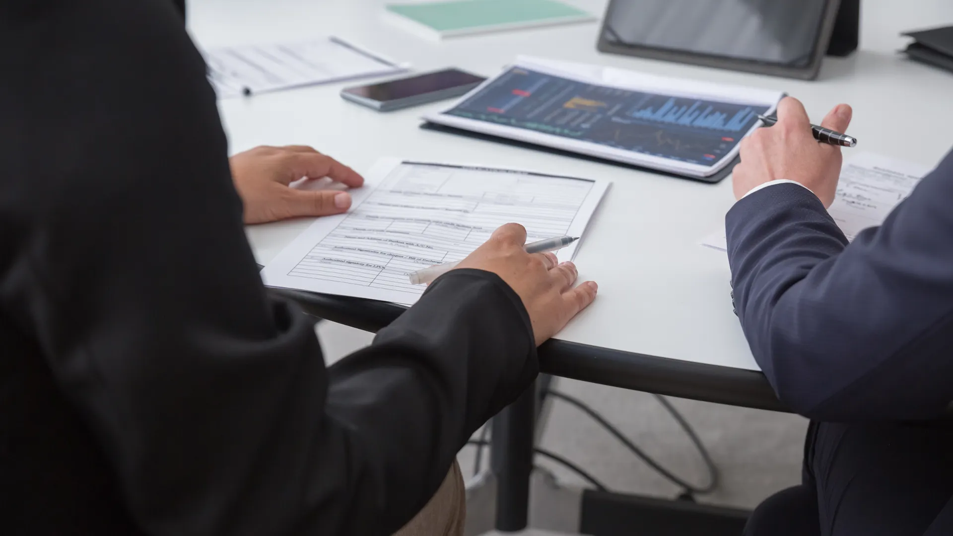 Close-up of professionals reviewing documents in an office setting, focused on analytics