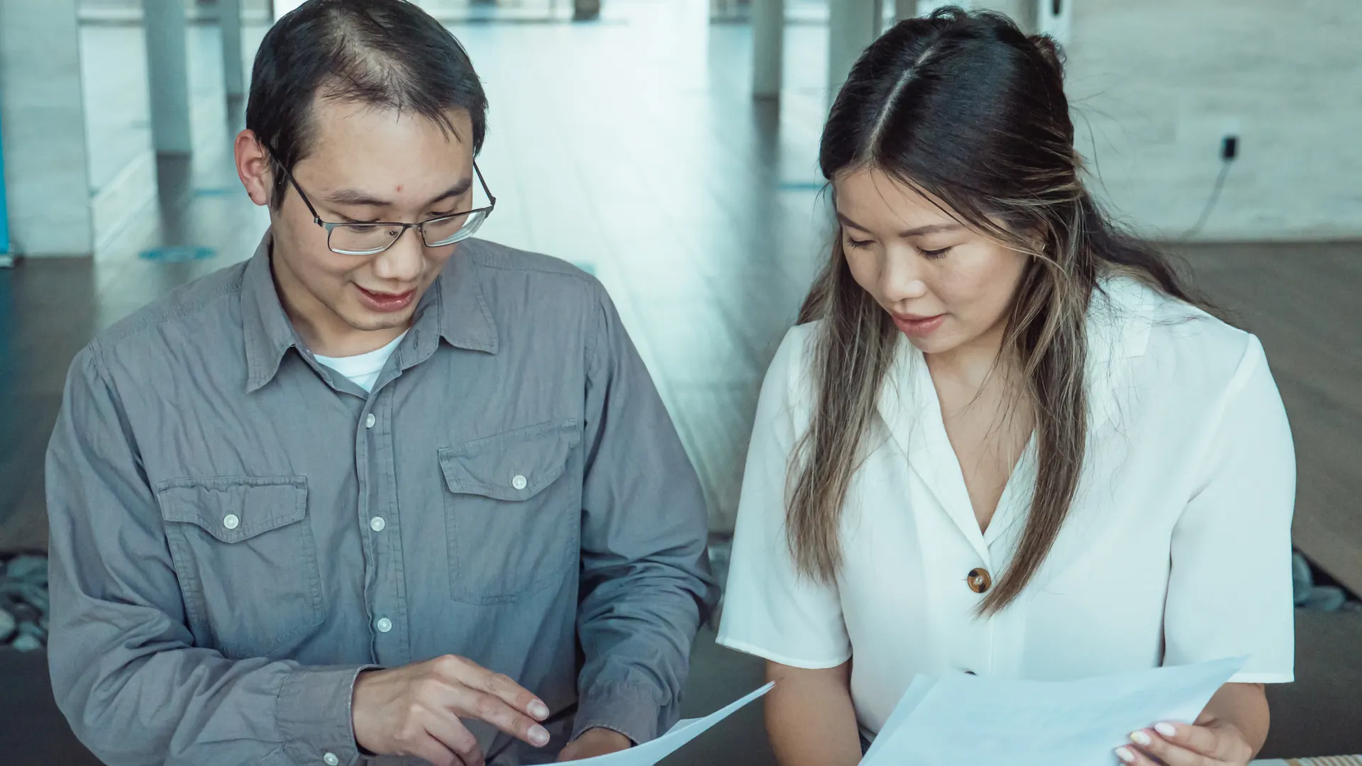 Two coworkers reviewing documents in a modern office, focused on teamwork and planning