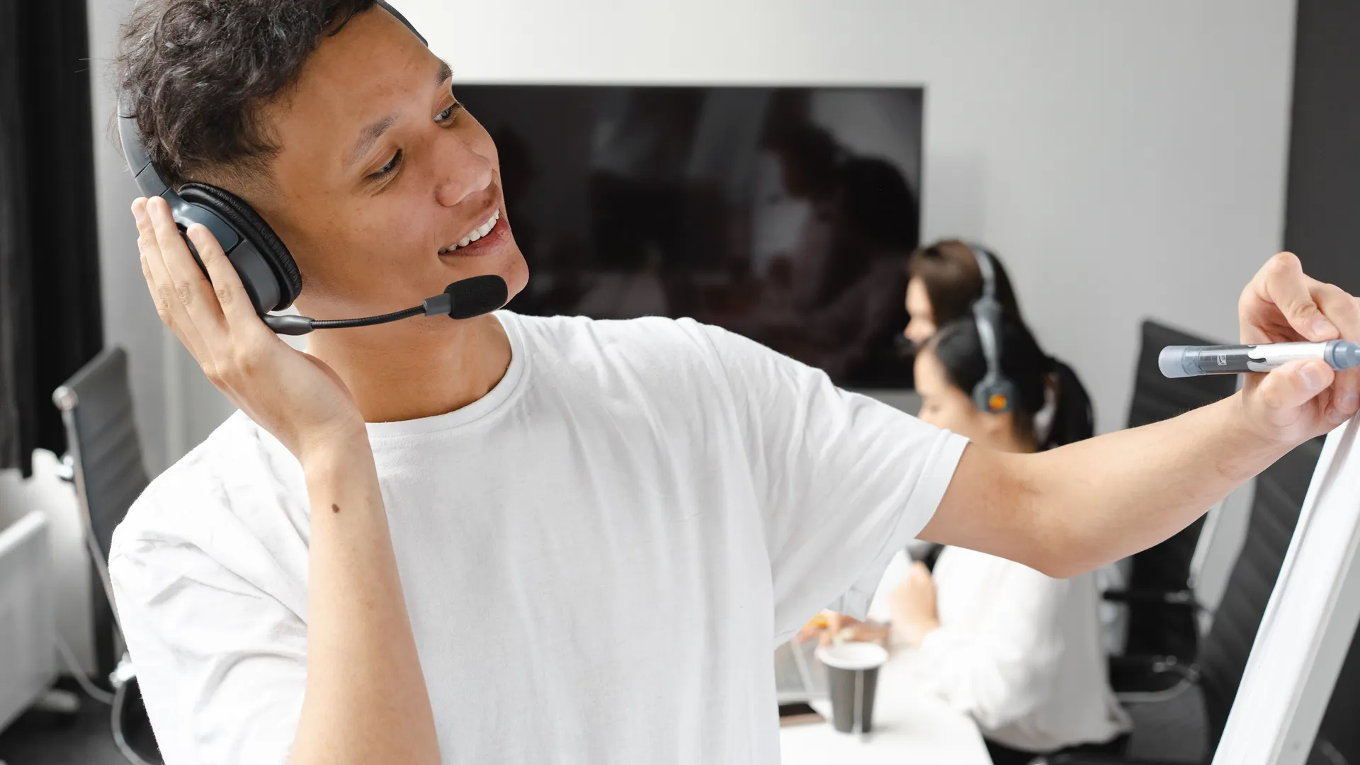 Man in office using headset and whiteboard for online teaching session