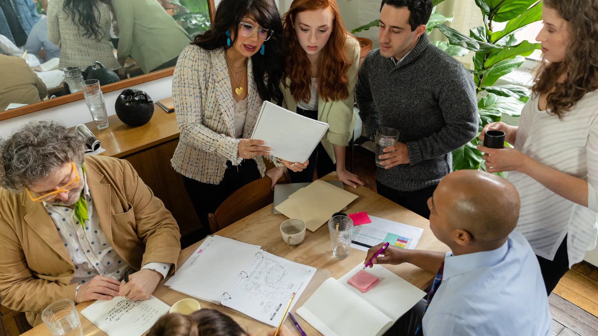 A diverse team discusses documents around a table