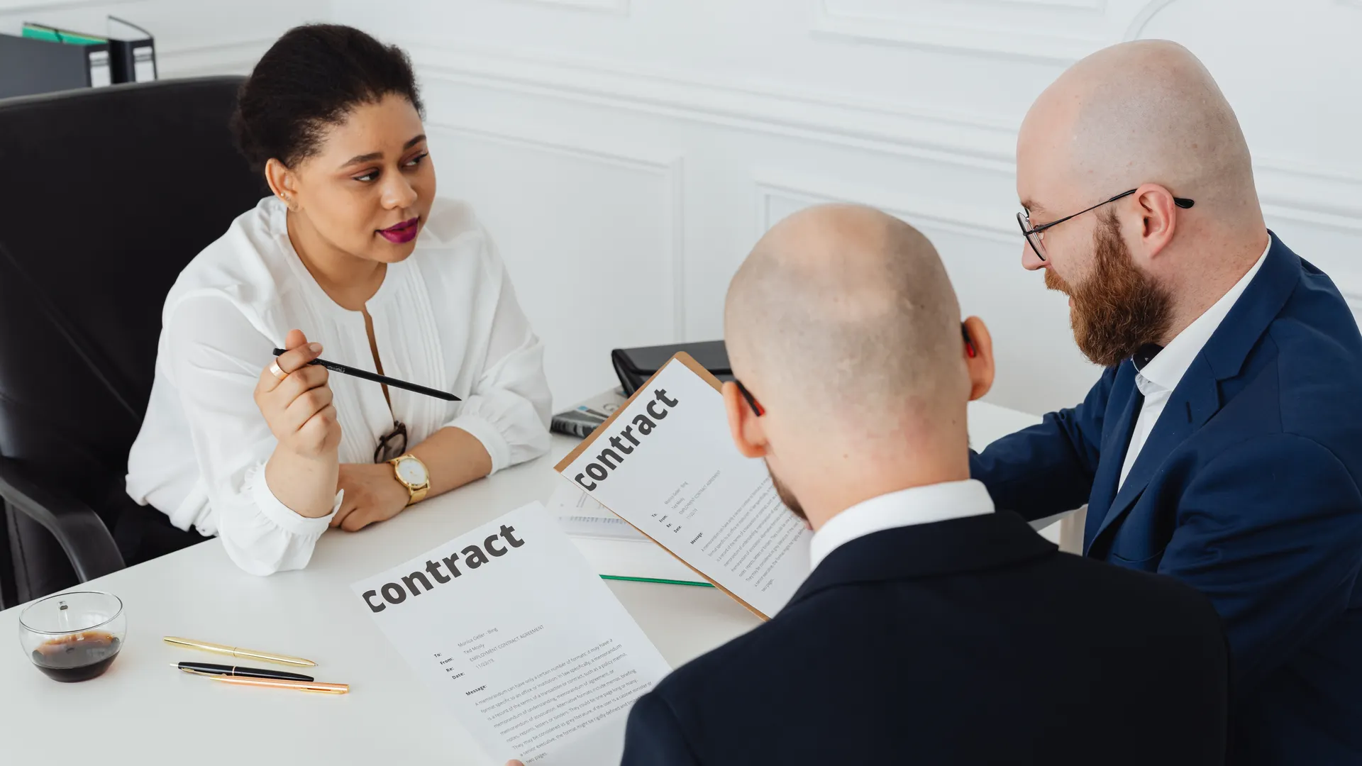 Three business professionals in discussion over a contract in a modern office setting