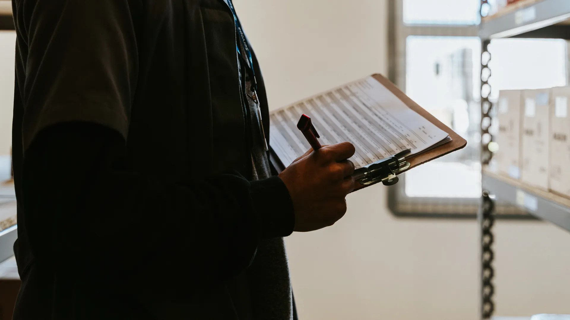 Industrial worker managing inventory in a warehouse with a clipboard and checklist