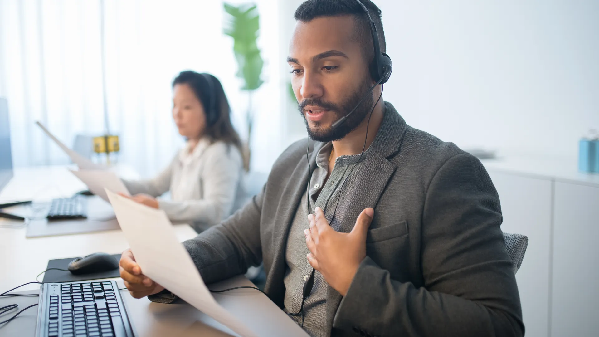 Businessman working at a call center desk, wearing a headset and reading documents