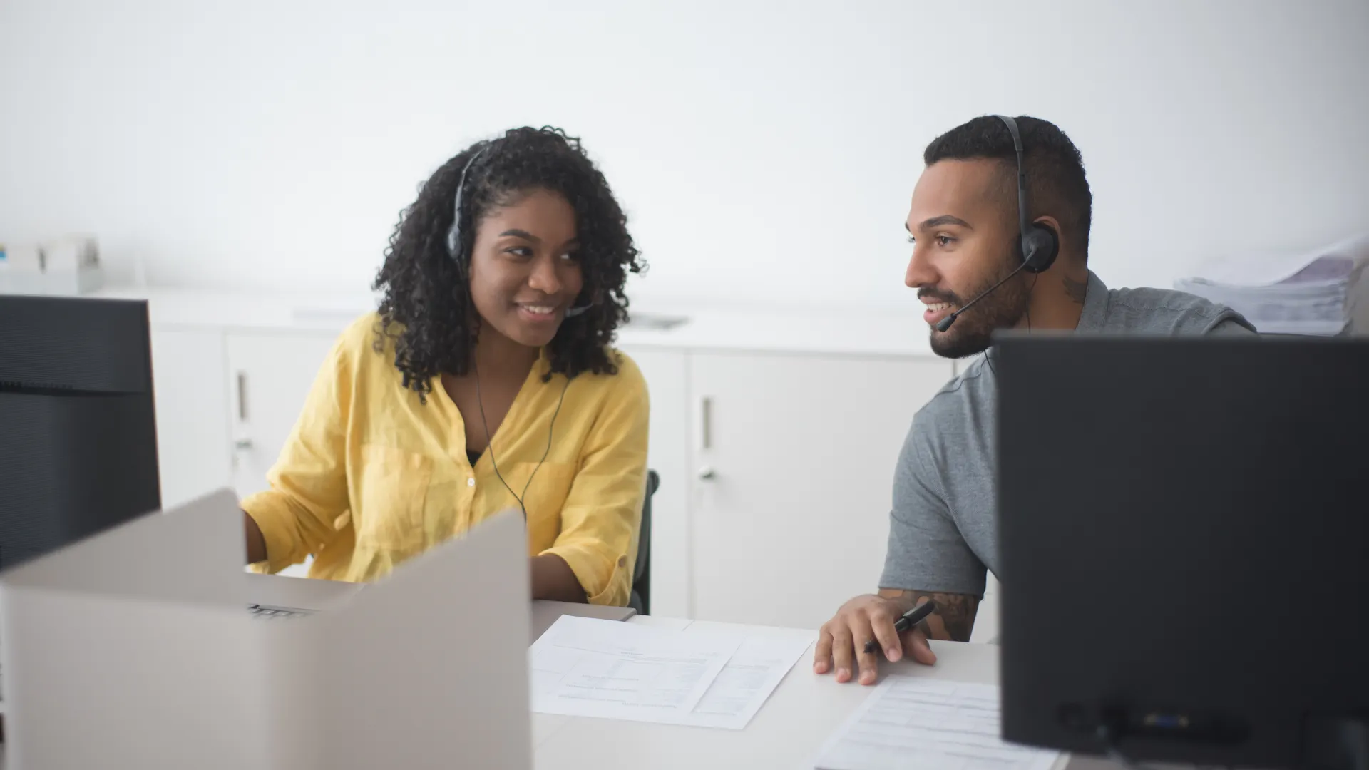 Two call center agents working together with headsets in a modern office environment