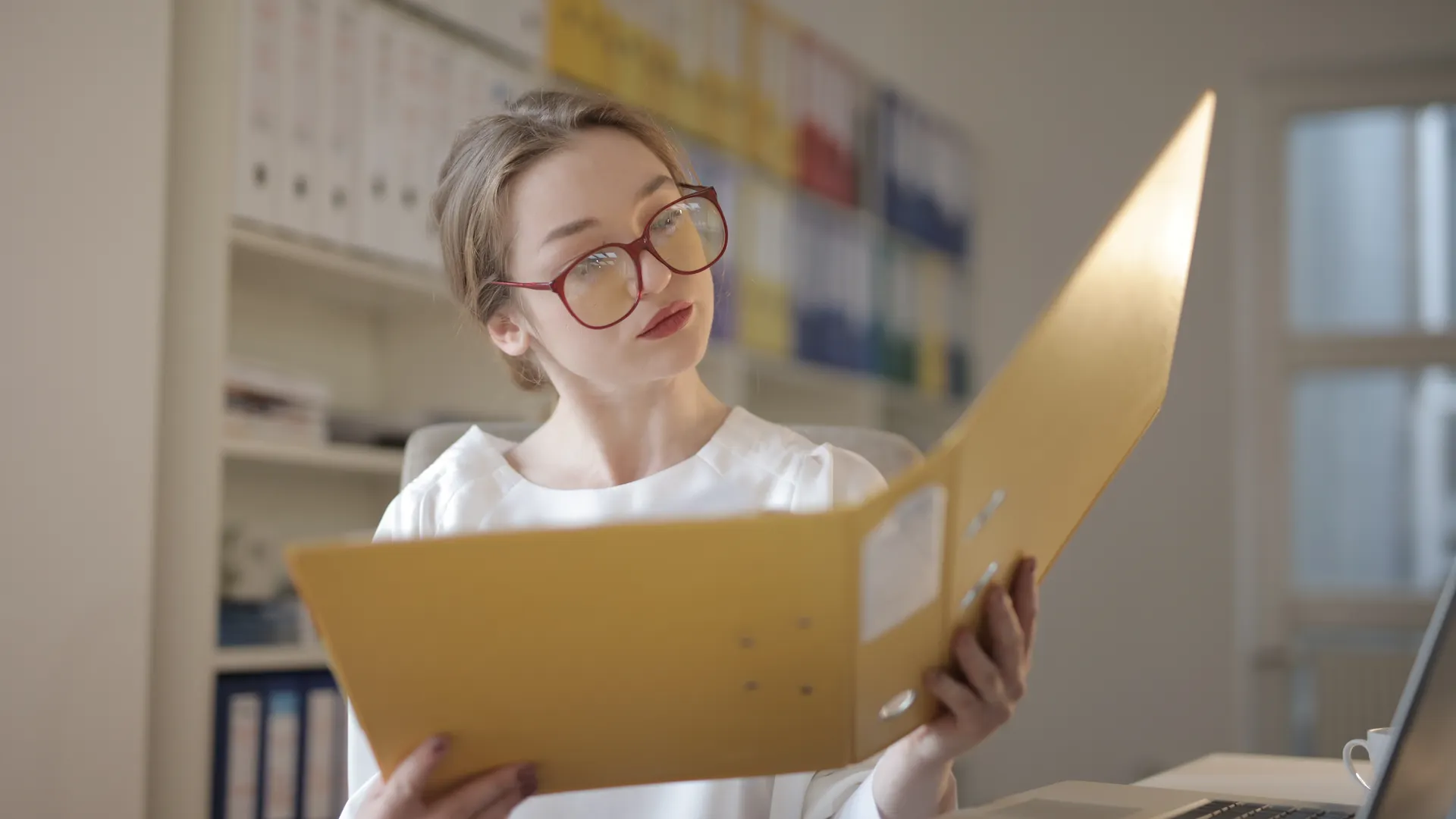 Caucasian woman intensely reading documents in an office setting