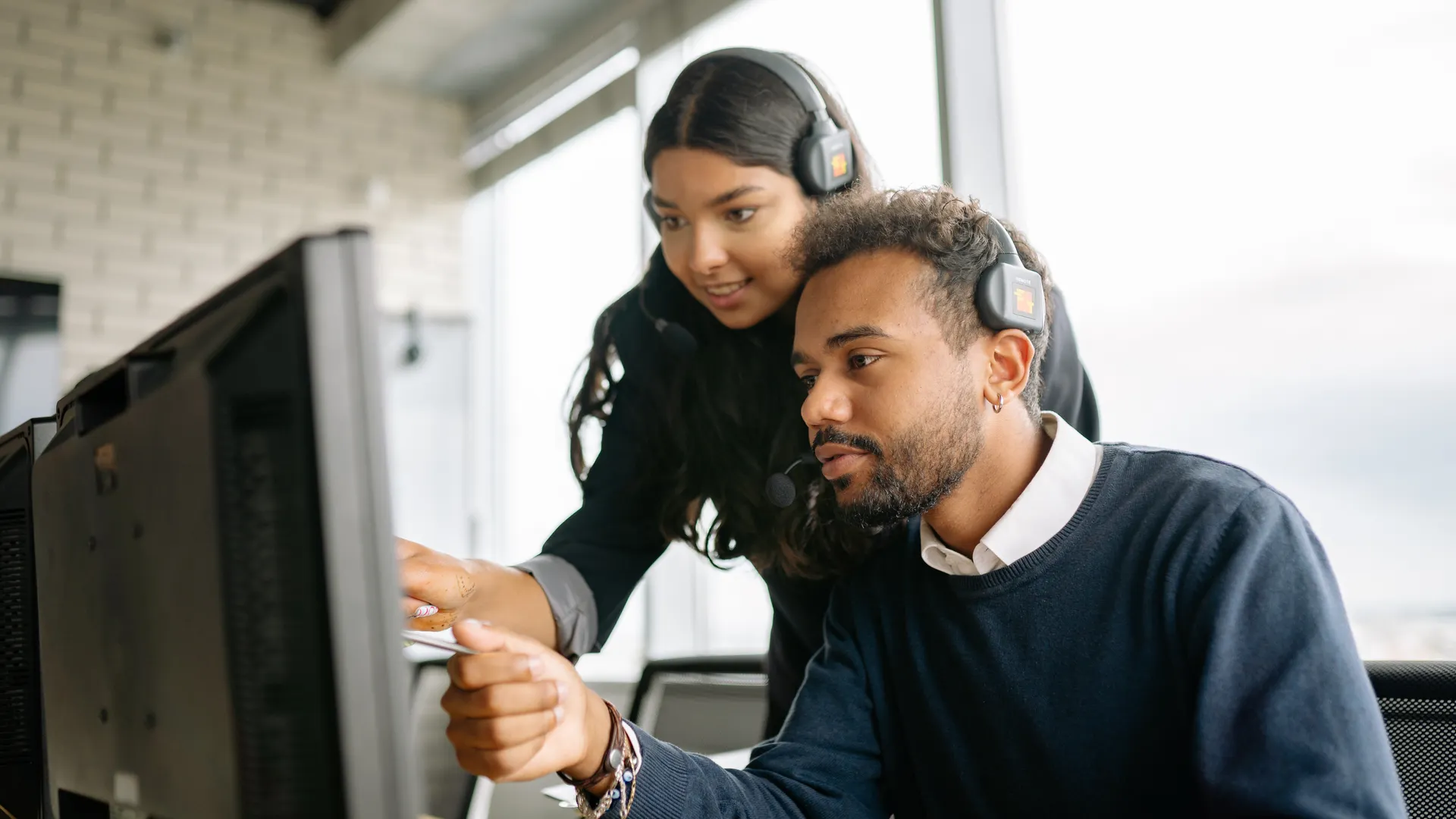 Two call center employees working together with headsets in a modern office setting