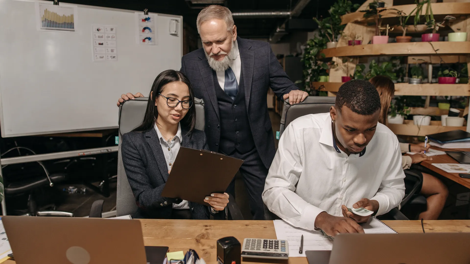 A diverse group of professionals working in a modern office with laptops and documents