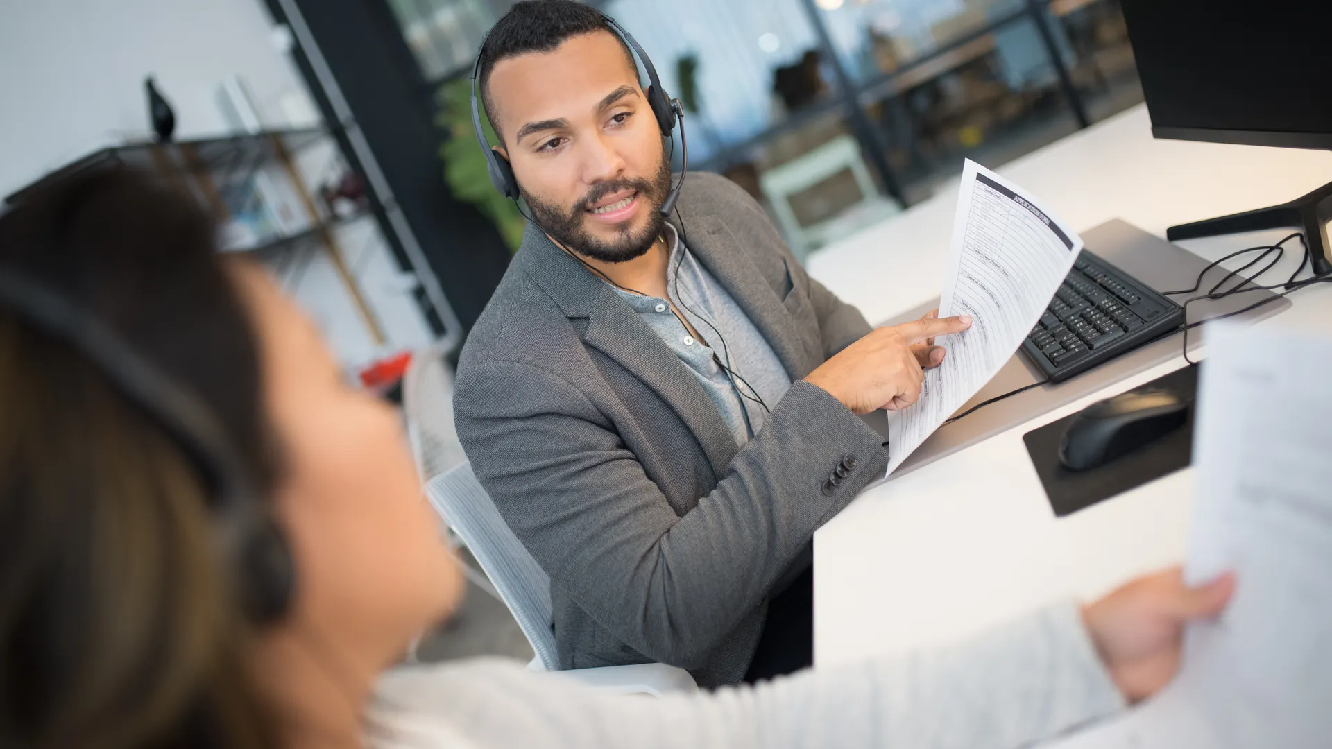 Colleagues discussing documents with headsets in a modern office setting