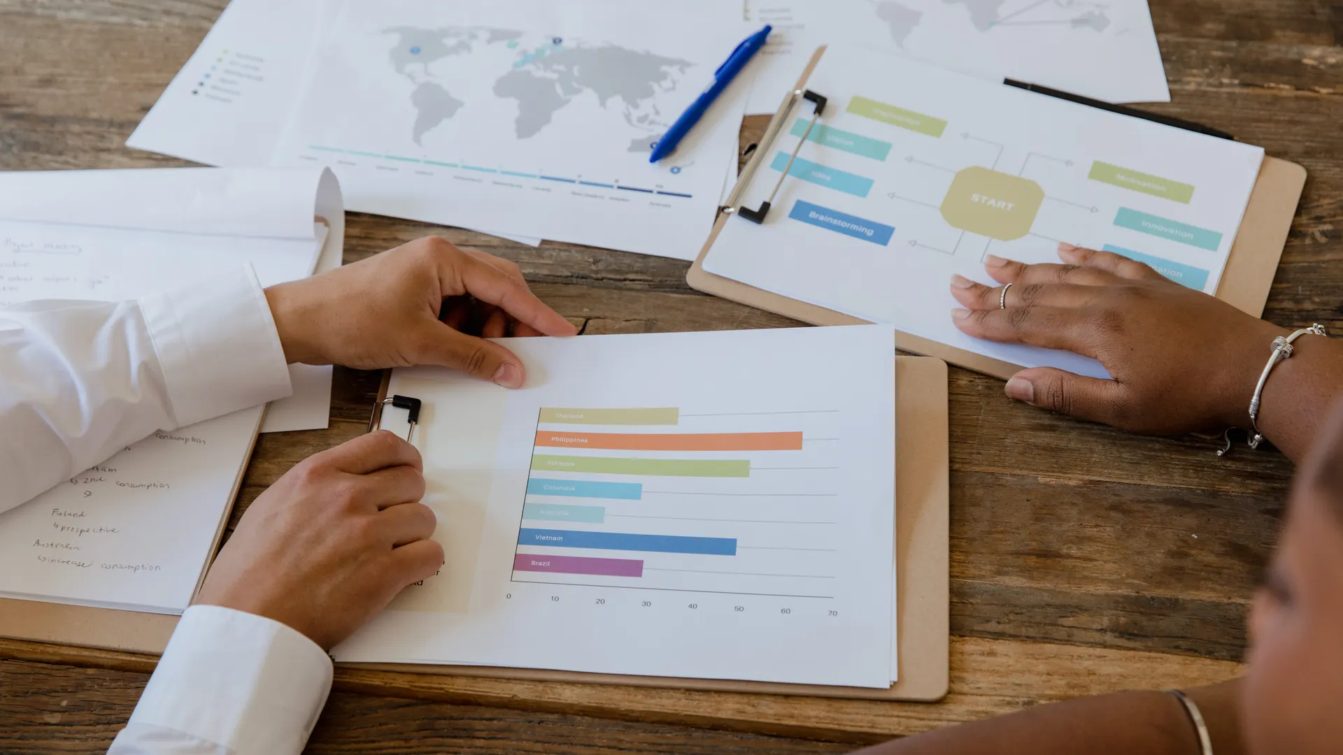 Top view of colleagues discussing charts and graphs on a wooden table during a business meeting