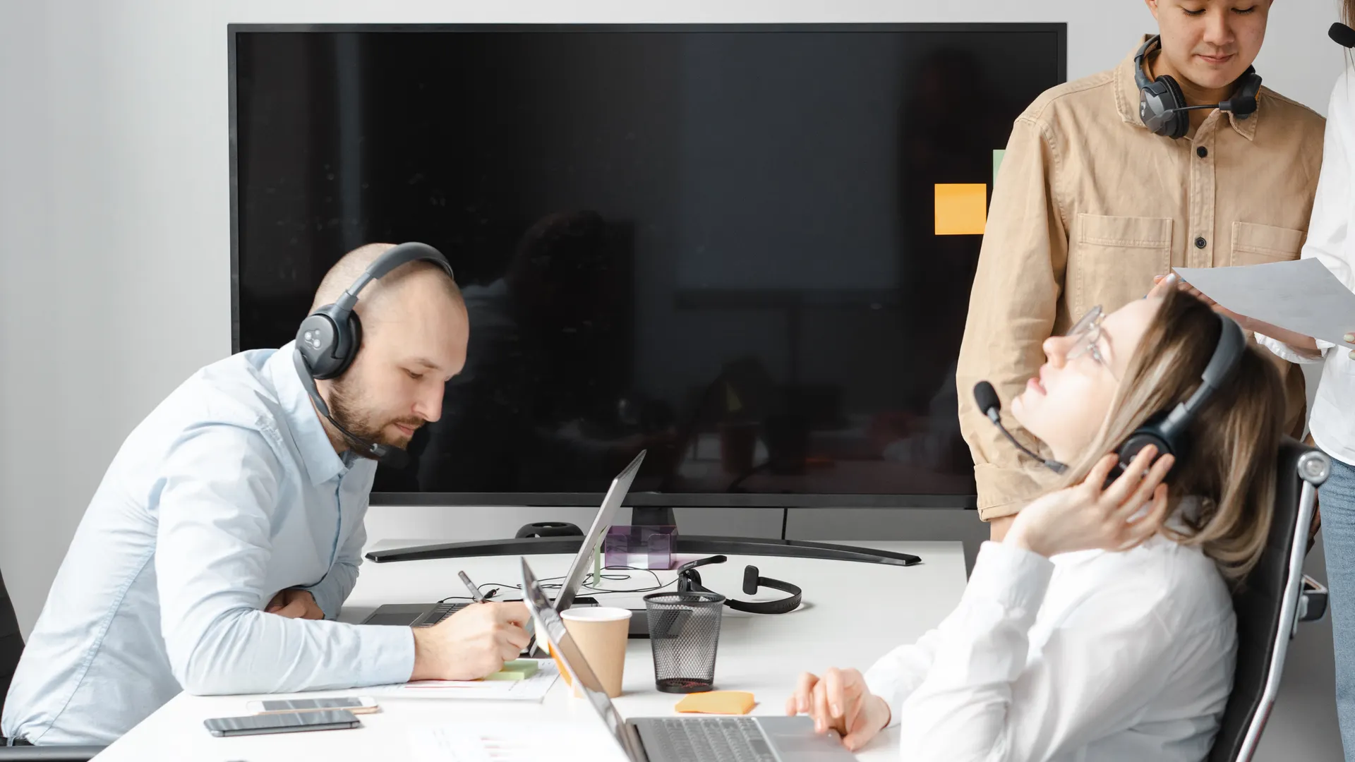 Employees in a modern office setting working with headsets and laptops, demonstrating teamwork and