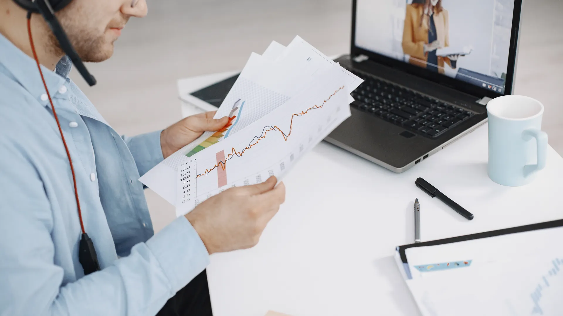 Business professional analyzing charts during a remote meeting with video call and headset