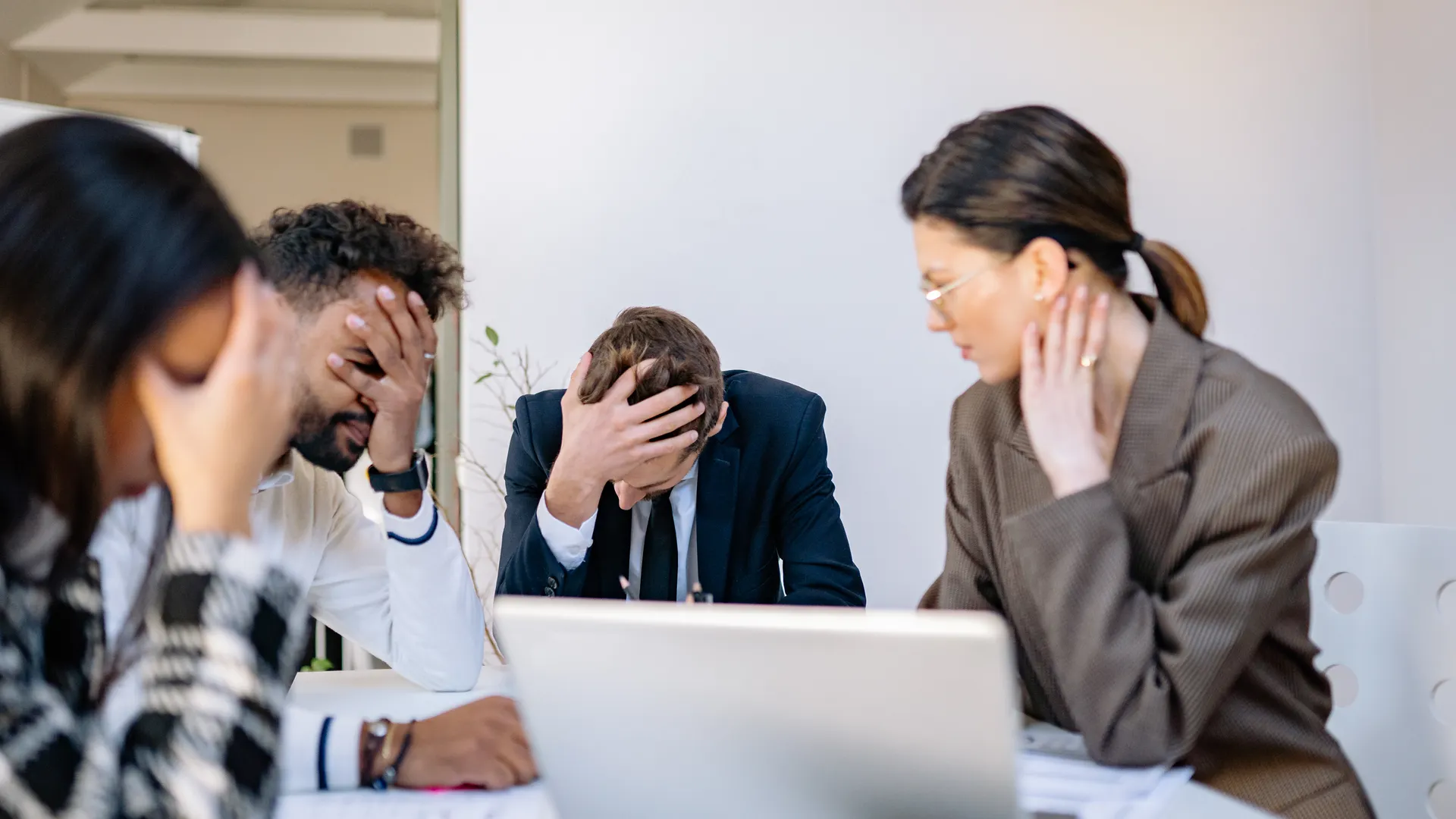 A group of stressed business professionals in an office setting, overwhelmed by work