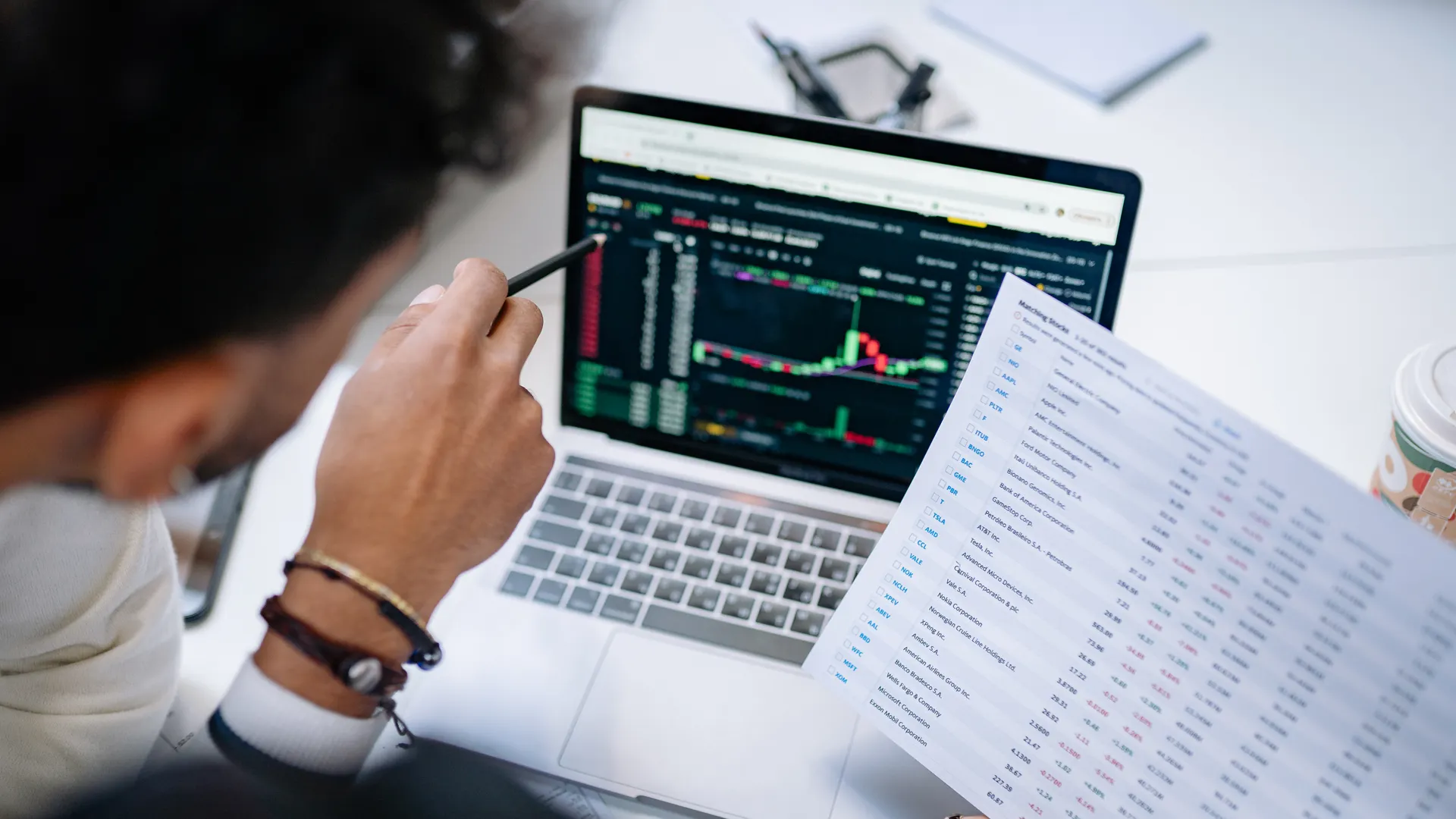 A professional analyzing stock market data on a laptop screen with financial documents