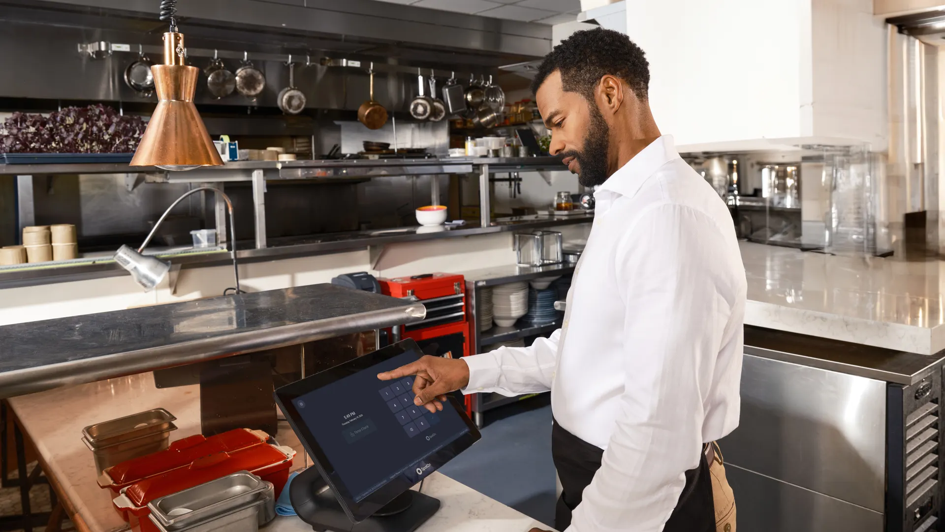 A restaurant worker operates a point of sale system in a commercial kitchen setting