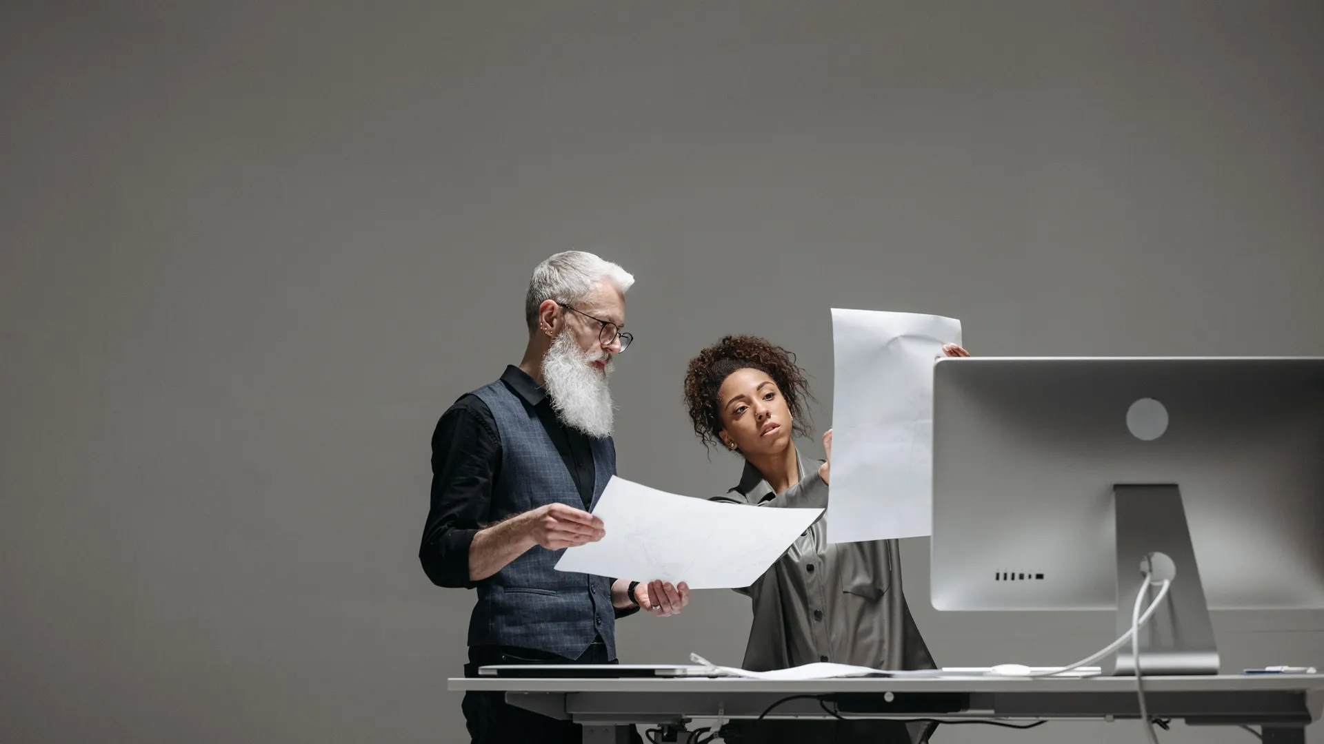 Two professionals collaborate on project plans at a computer workstation