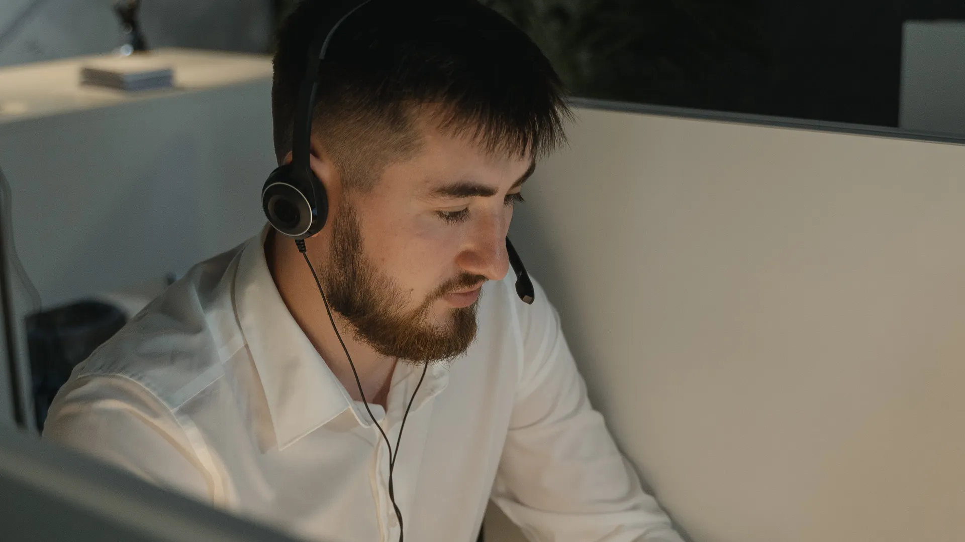 A bearded man with a headset working attentively in a call center
