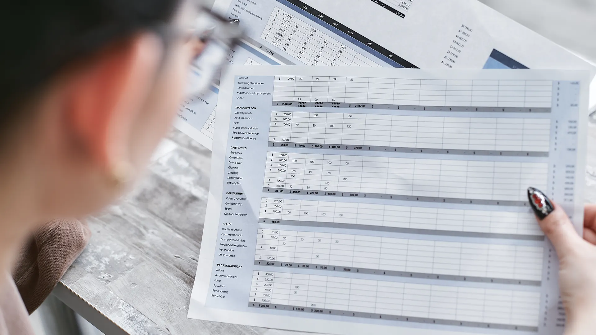 A businesswoman reviewing financial spreadsheets with charts and graphs in an office setting