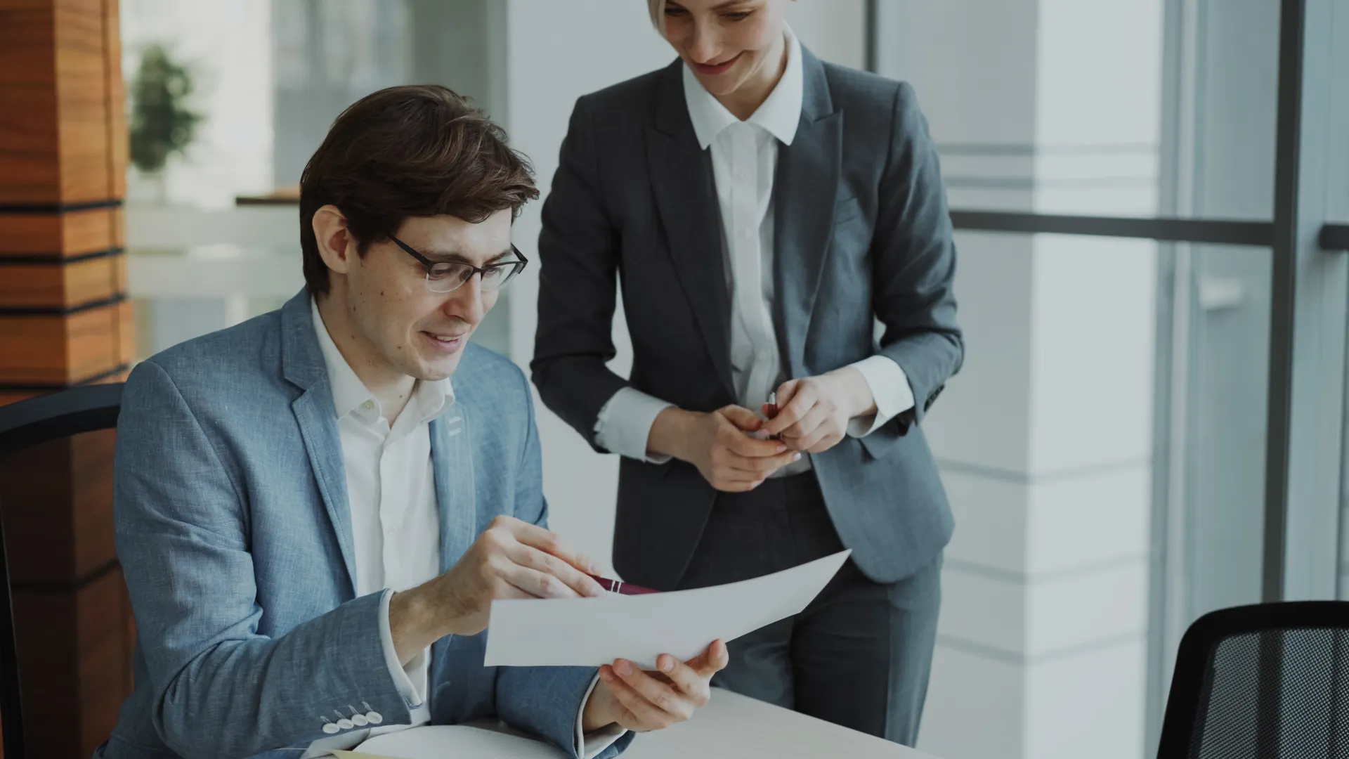 Two business professionals discussing a document in a modern office setting