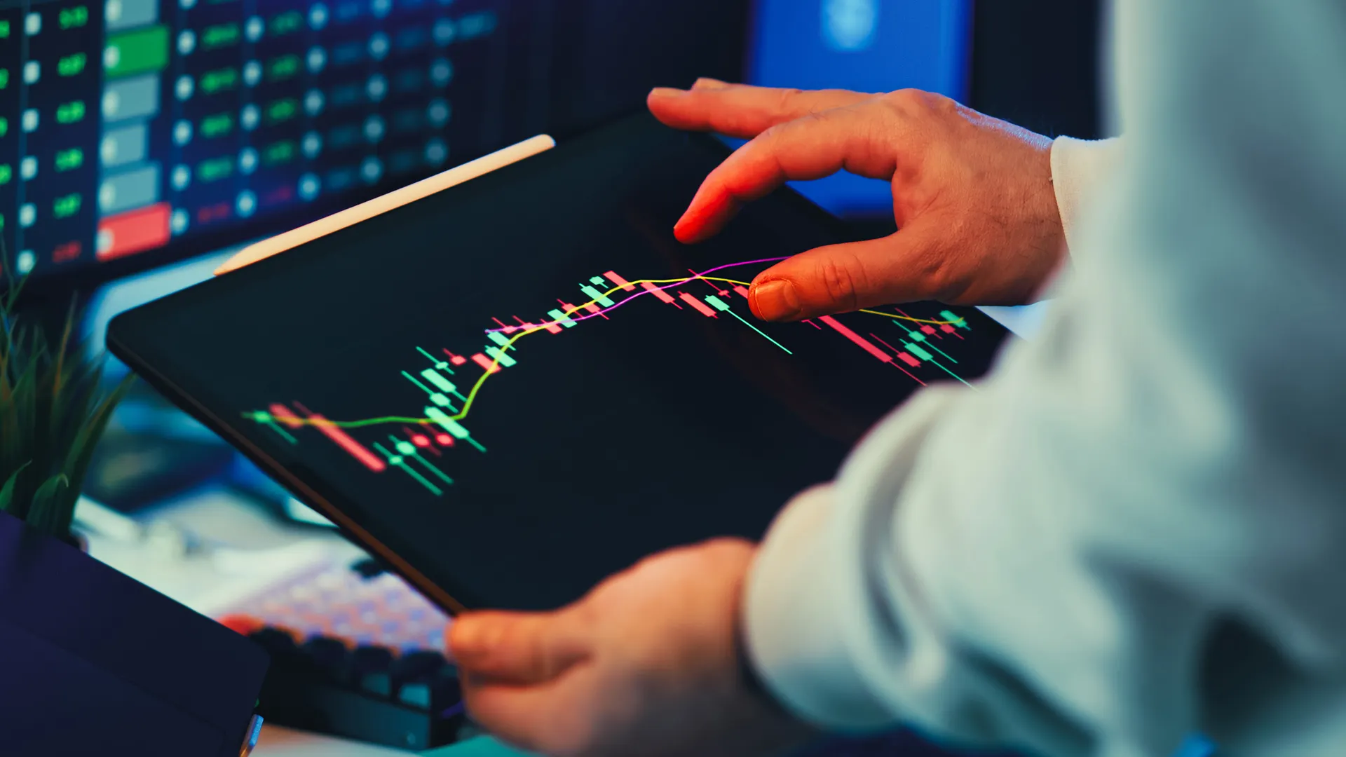 A close-up of a person using a tablet to analyze stock market trends and charts indoors