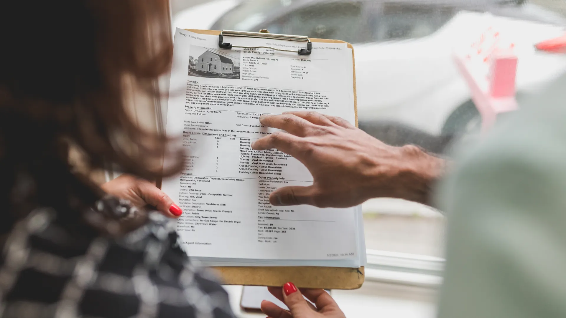 Real estate agent discussing property details with client using a clipboard indoors