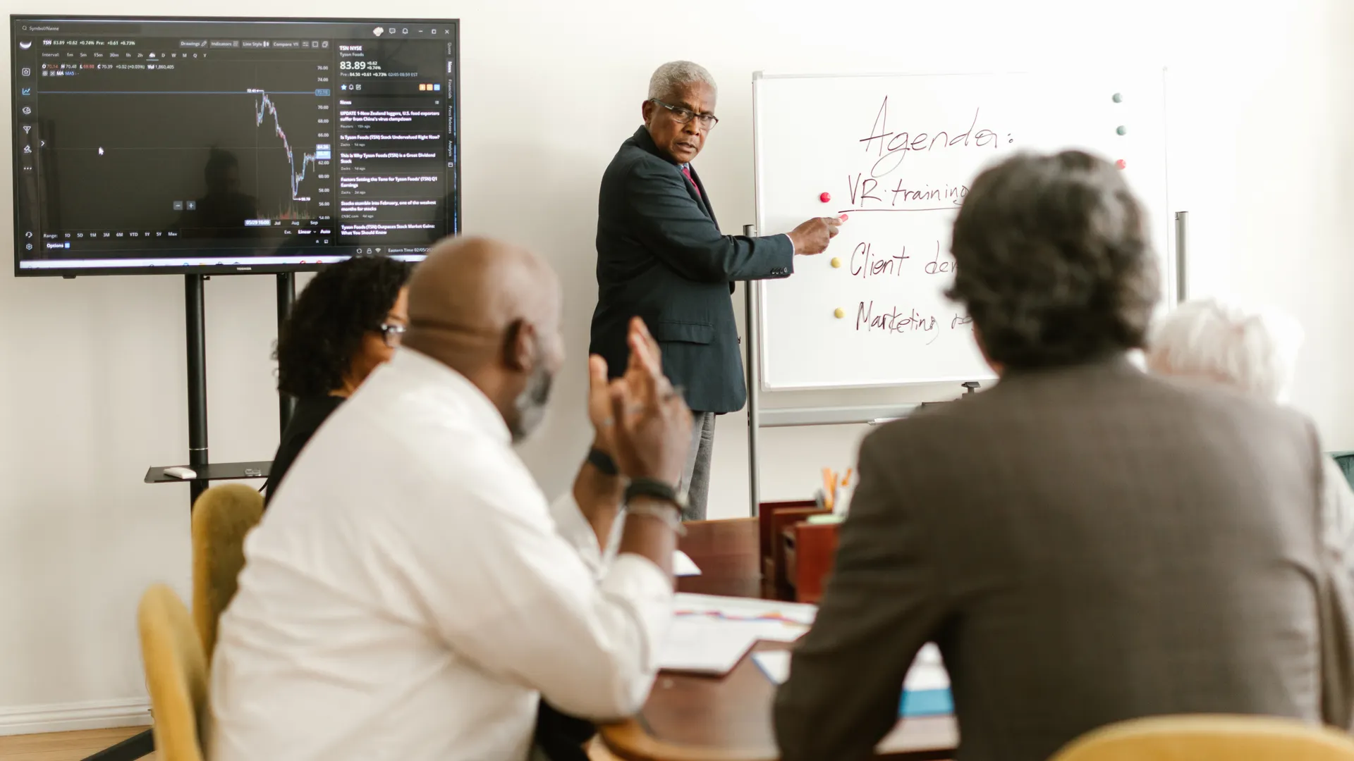 A diverse group of professionals having a meeting in an office setting, discussing on a whiteboard