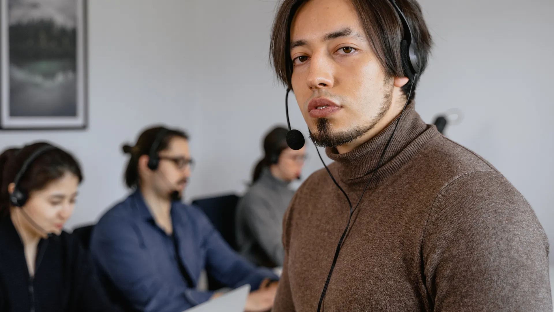 Focused call center team working attentively with headsets on in office