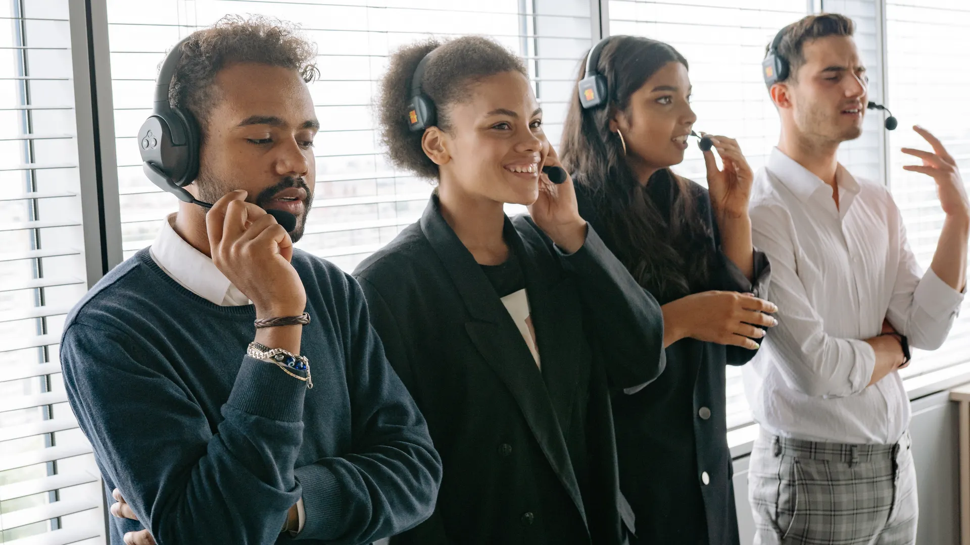 Diverse call center team collaborating in a modern office, wearing headsets and smiling