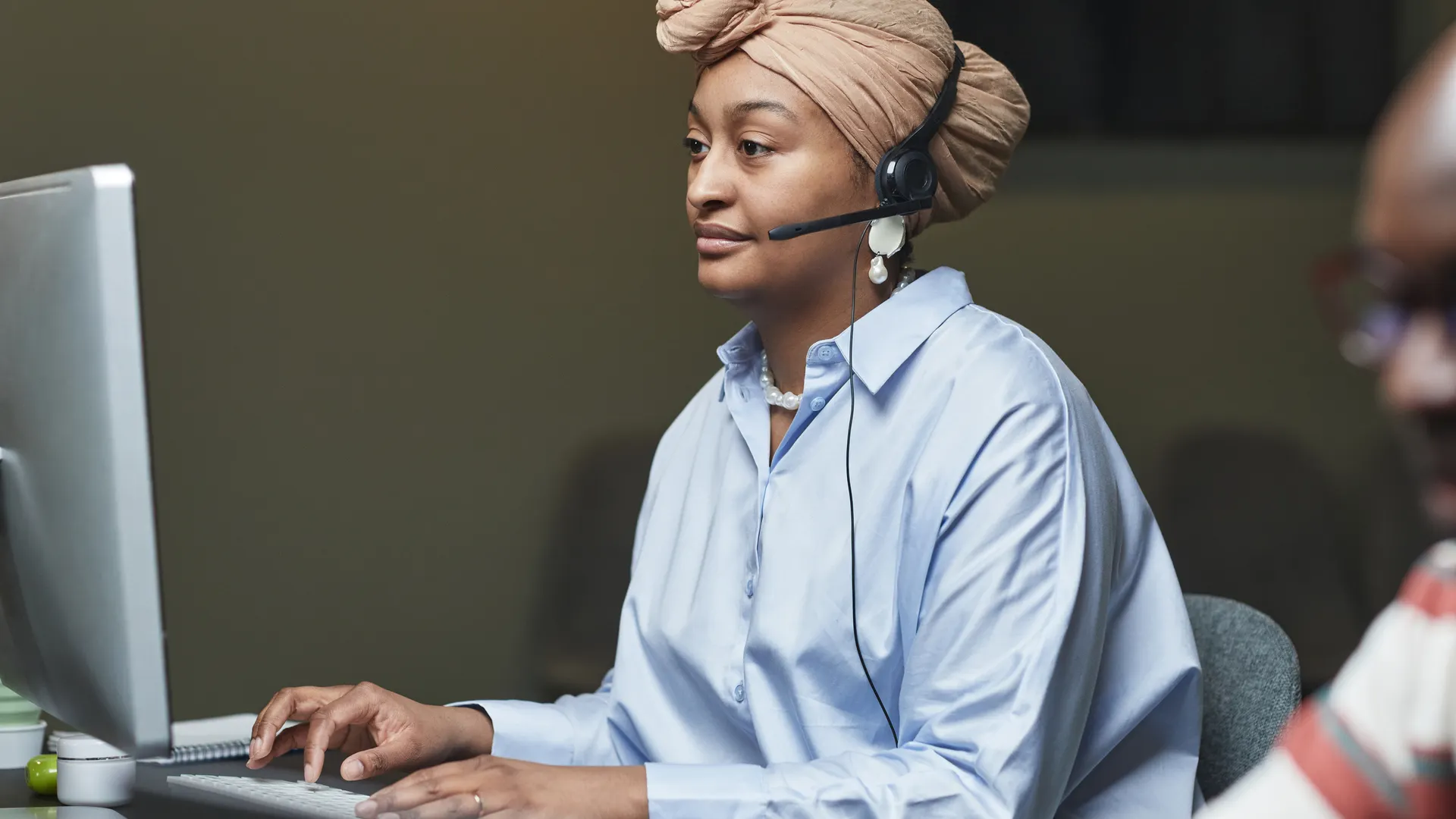 Focused employee in an office setting using a computer and headset