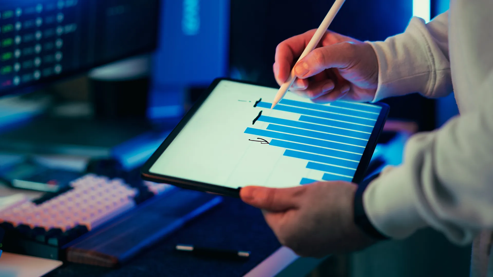 A person using a stylus on a tablet showing a business graph in an office setting