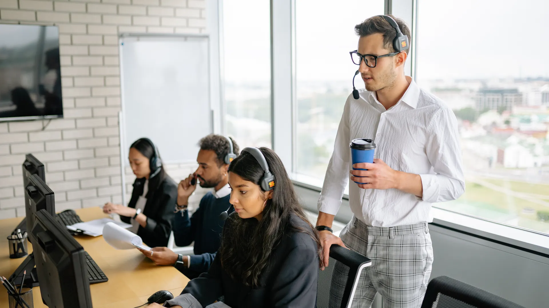 A diverse group of employees working together in a bright, modern call center with headsets