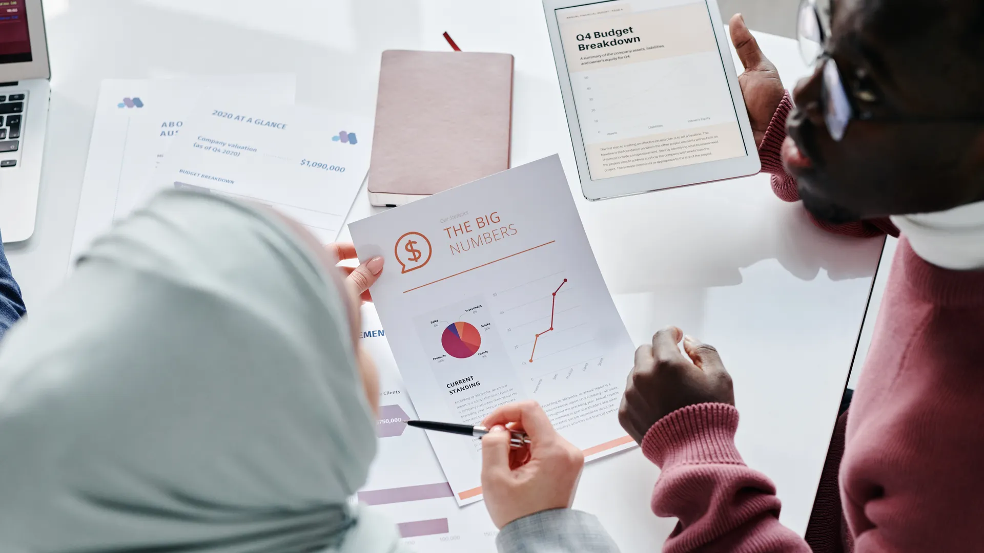 Two colleagues reviewing financial documents and graphs during an office meeting