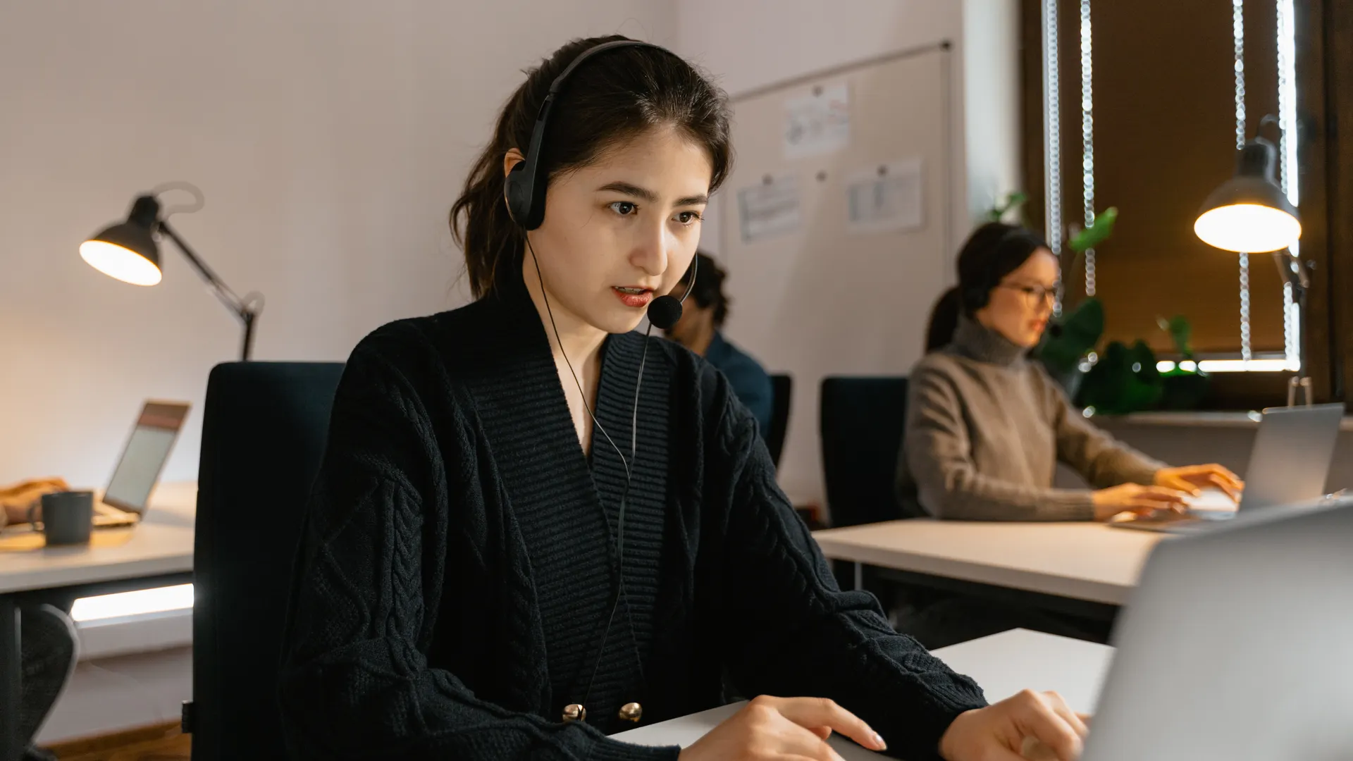 Focused call center agents working with headsets in a modern office environment