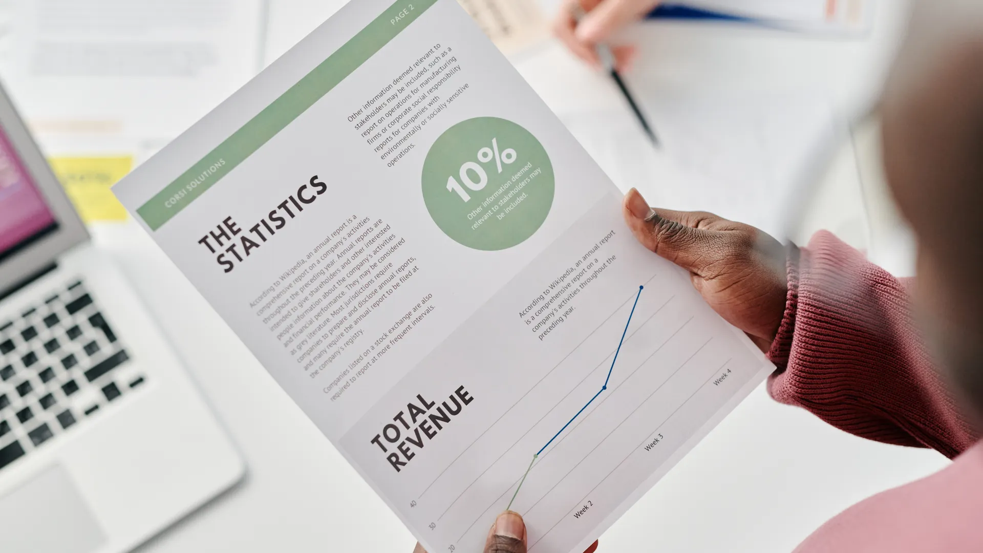 Hands holding a statistical report during a business meeting. Includes revenue graphs and analysis