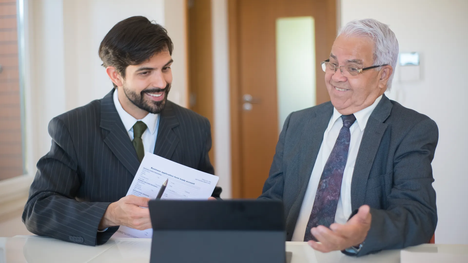 Two businessmen discussing a real estate deal in a modern office setting