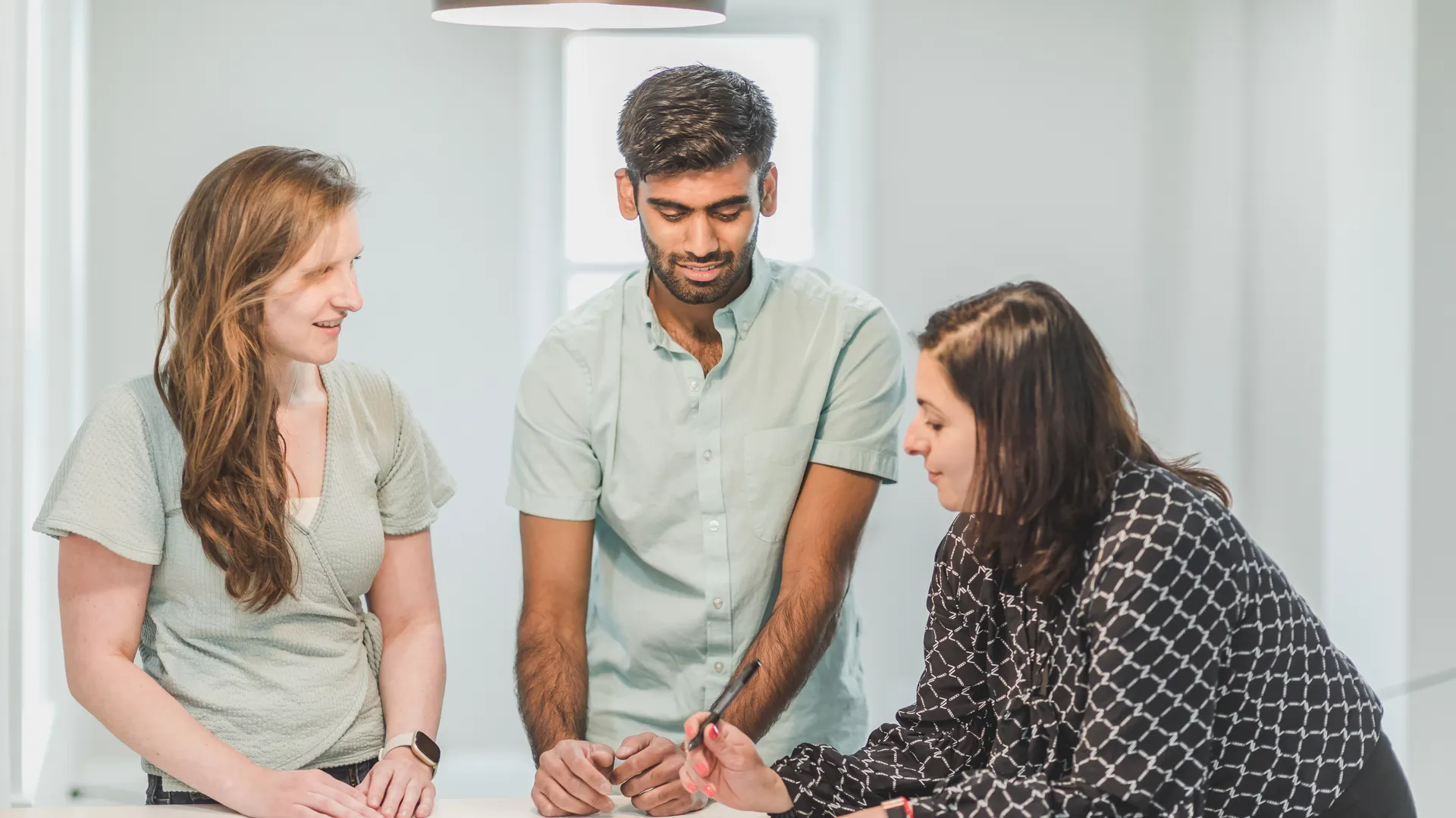 Three professionals engaged in a discussion indoors, possibly real estate related