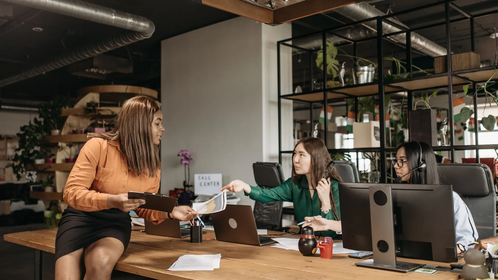 Diverse group of female professionals discussing work at their desk in a modern office setting