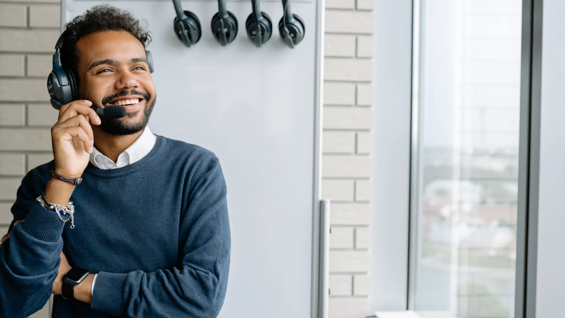 Happy call center agent wearing headphones, smiling in a modern office setting