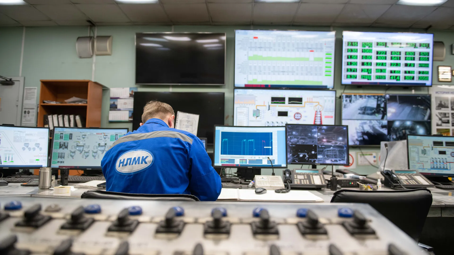 An engineer monitors multiple screens in an industrial control room, ensuring smooth operations