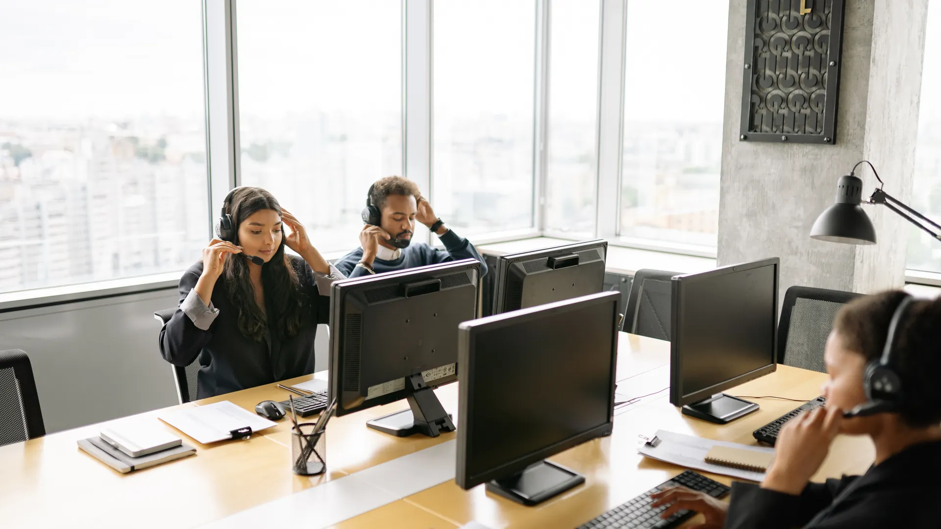 Focused call center agents working at computers with headsets in a bright office setting