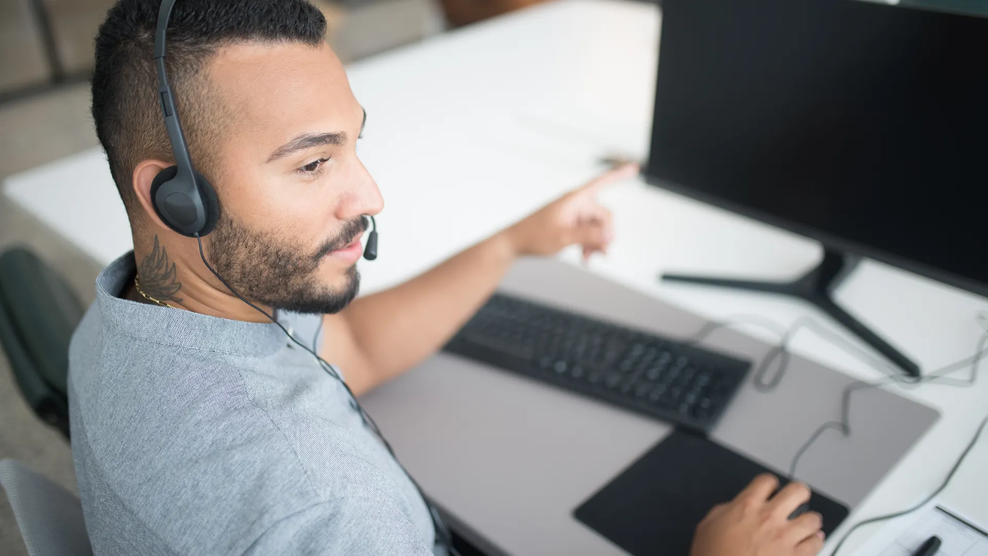 Customer service agent using a computer and headset within a modern office setting