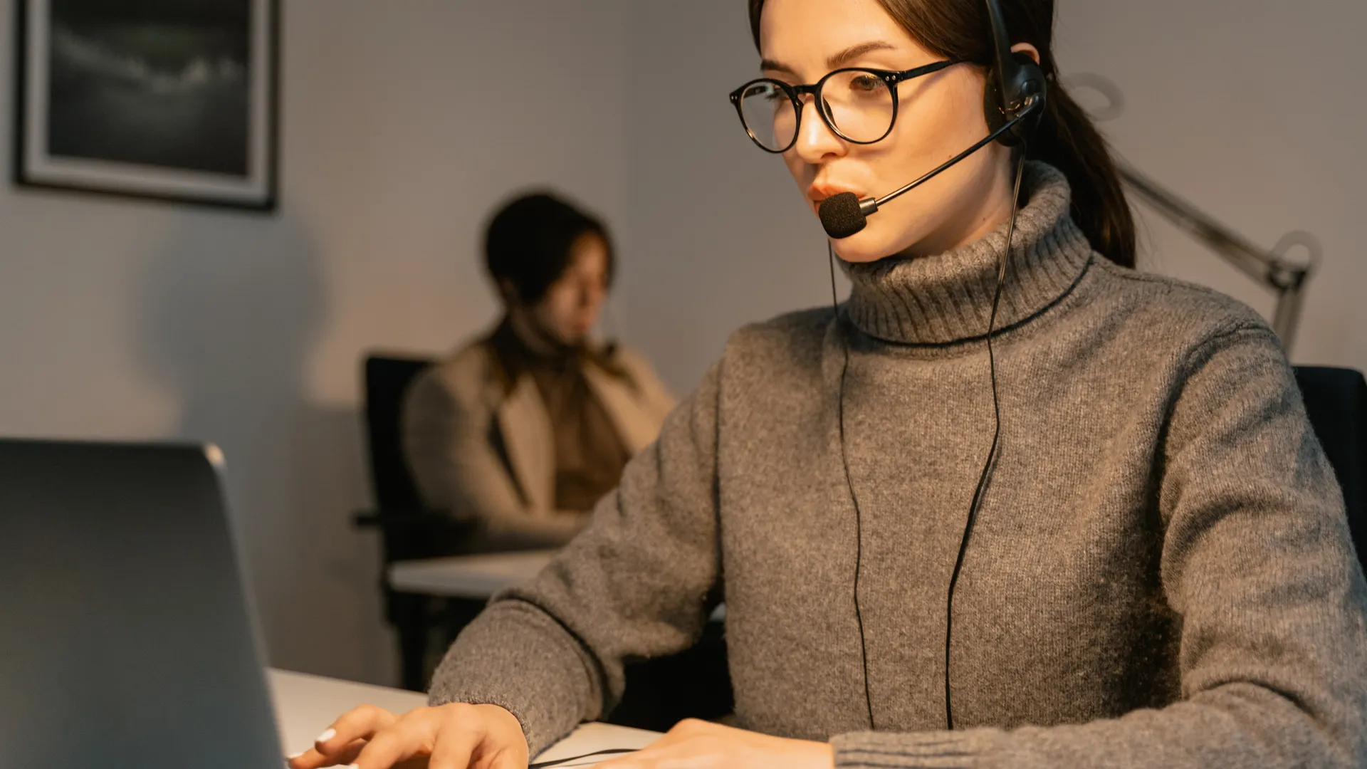 Professional woman wearing headset working in customer support, focused on her tasks