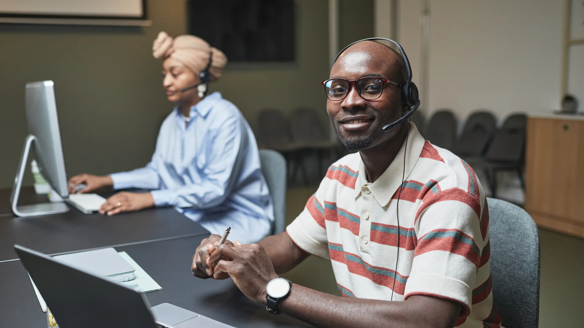 Two call center employees working at desks, focused and collaborative