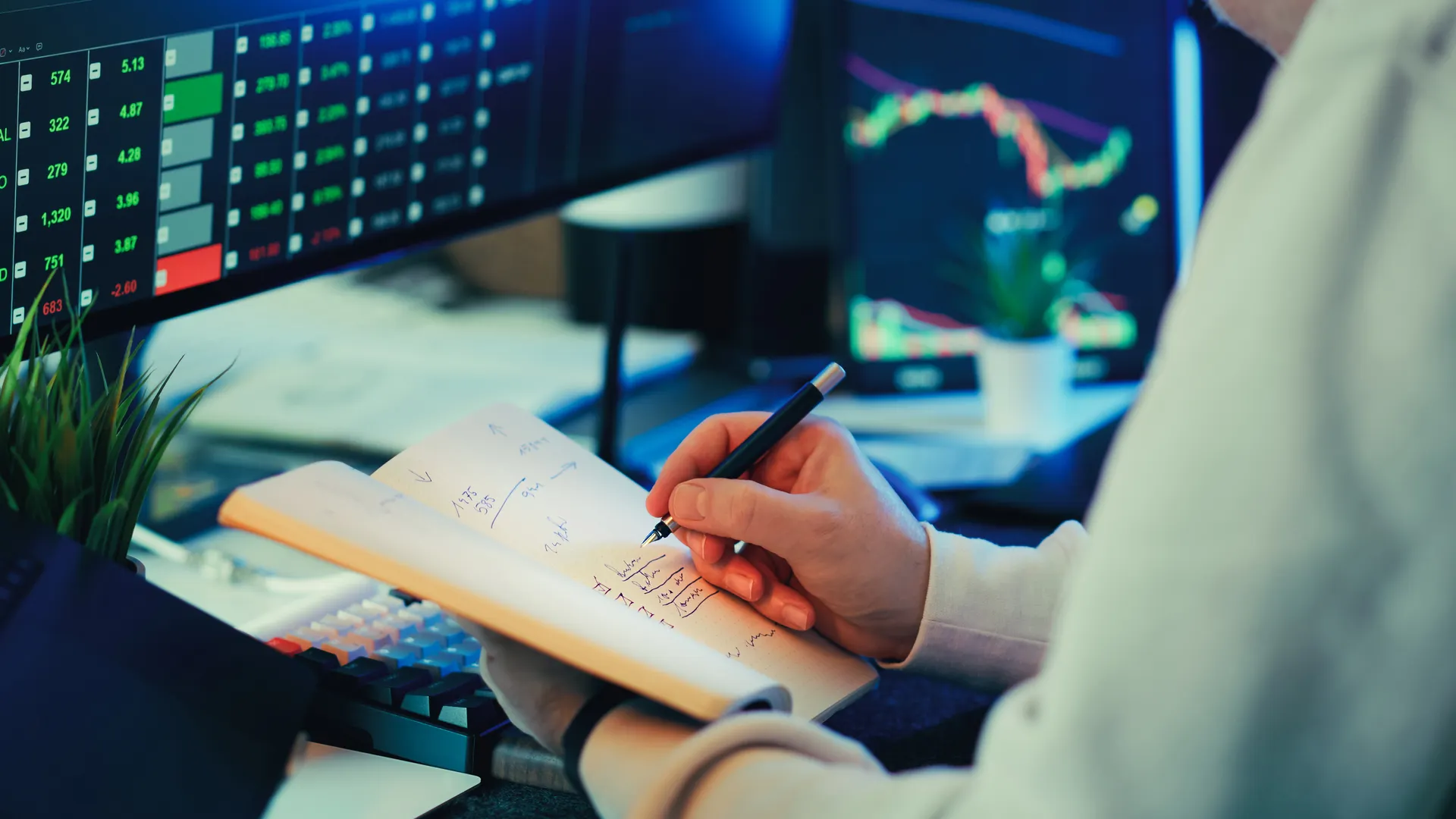 Person analyzing financial data on screens, making notes. Ideal for business and finance themes