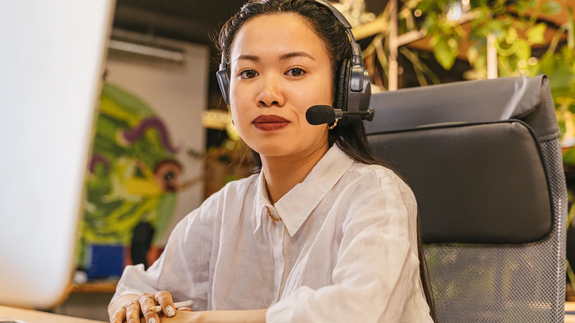 Asian woman in office wearing headset, working in a modern call center environment
