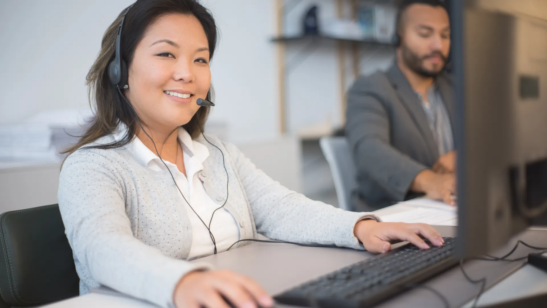 Two call center employees working with headsets in a modern office setting