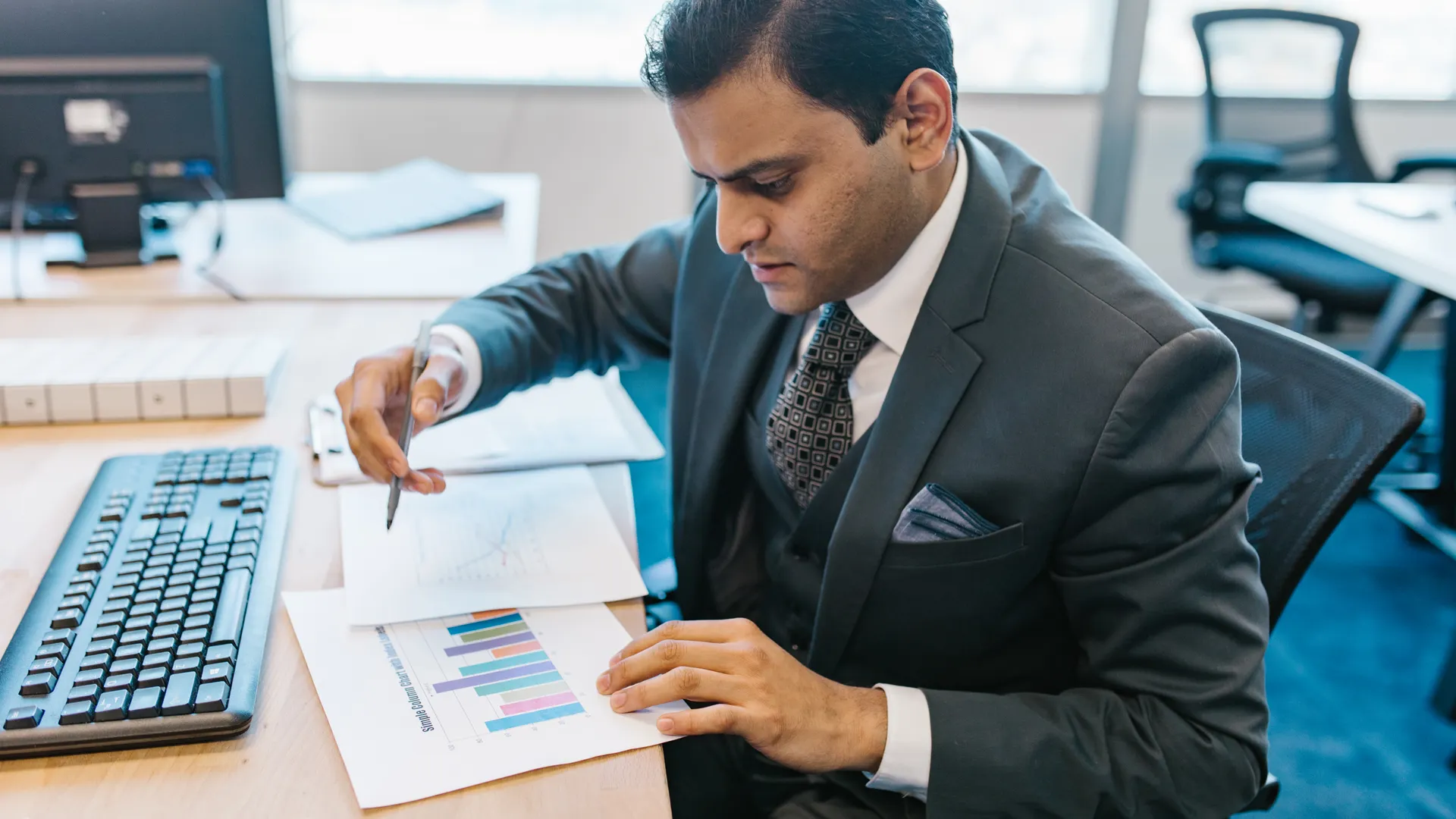 Business professional reviewing graphs and charts on a desk in a modern office setting