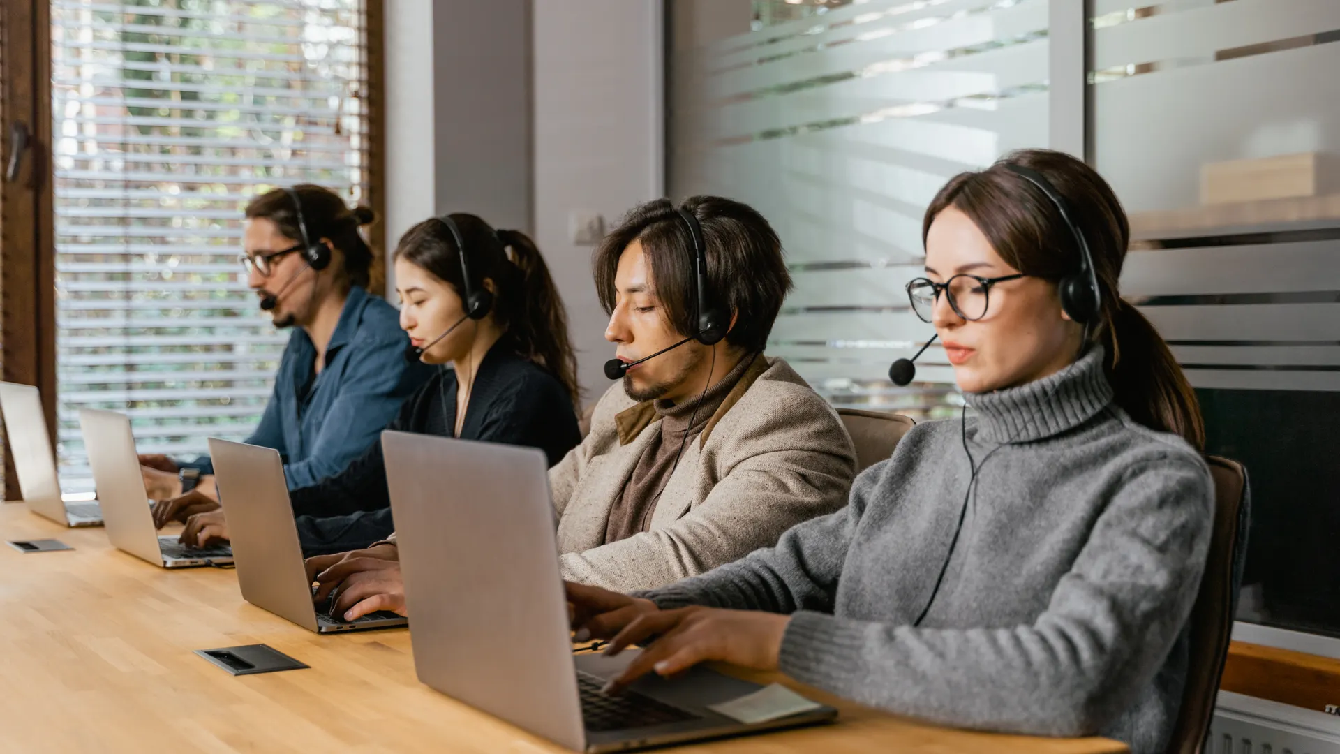 A diverse call center team uses laptops and headsets to provide customer support efficiently